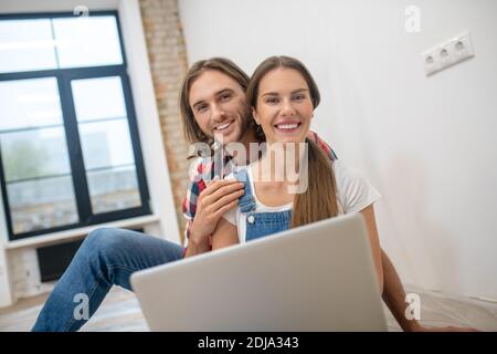 Young couple sitting on the floor and searching for something online Stock Photo