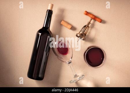 Wine tasting, top shot on a brown background. A cork, corkscrew, a bottle, and two glasses of red wine Stock Photo