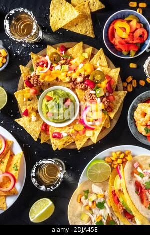 Mexican food, various dishes, overhead shot on a black background. Nachos, tacos, tequila Stock Photo