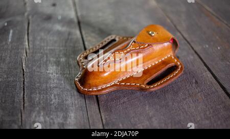 Handmade Leather Pancake Knife Sheath on wooden background. Stitching by hand. Stock Photo
