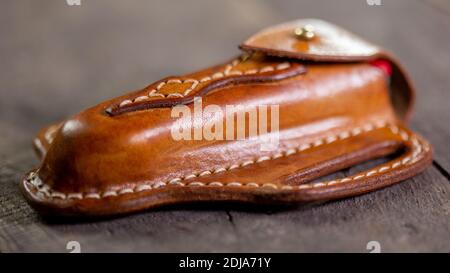 Handmade Leather Pancake Knife Sheath on wooden background. Stitching by hand. Stock Photo