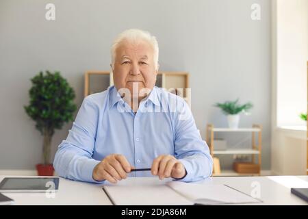 Senior businessman worker sitting and looking at camera at desk Stock Photo