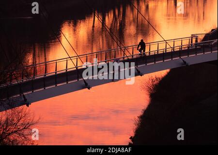 Dresden, Germany. 14th Dec, 2020. A cyclist stands out as a silhouette on the pier bridge at sunrise. Credit: Sebastian Kahnert/dpa-Zentralbild/dpa/Alamy Live News Stock Photo