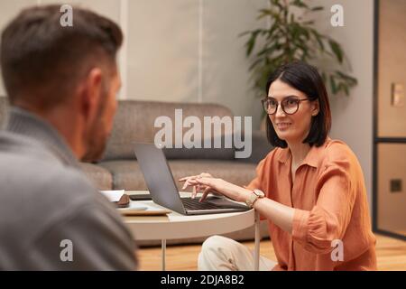 Portrait of modern couple working from home, focus on adult business woman using laptop while sitting on floor Stock Photo