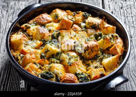 Italian spinach strata of soaked overnight cubed sandwich bread and baked with chopped spinach and shredded cheese with mustard served on a black baki Stock Photo