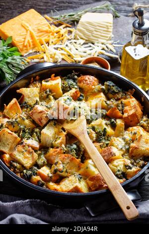 Italian spinach strata of soaked overnight cubed sandwich bread and baked with chopped spinach and shredded cheese with mustard served on a black baki Stock Photo