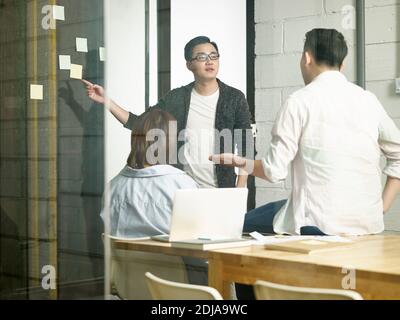 three young asian entrepreneurs meeting in office discussing business Stock Photo