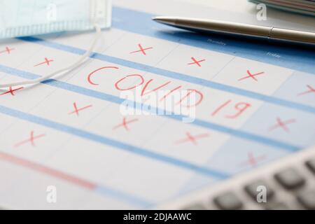 Pen lying on table with calendar with red strikethrough dates during covid19 pandemic Stock Photo