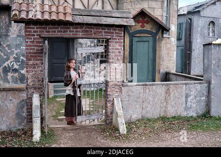Portrait woman parishioner in medieval dress at the door  in the courtyard of the old European Church Stock Photo