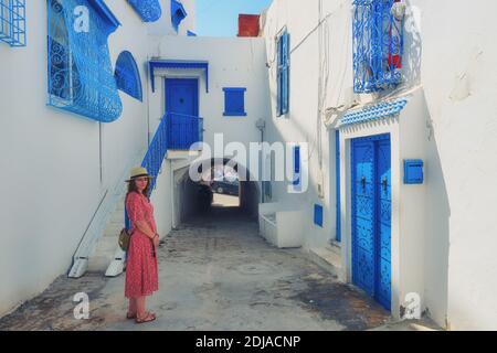 Tourist stands in the courtyard with blue windows and doors with Arabic ornaments. Texture of Islamic symbols in Sidi Bou said, Tunisia, Africa Stock Photo