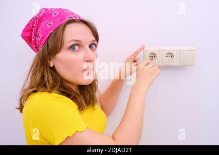 Woman with a fright repairs a power outlet with a screwdriver Stock Photo