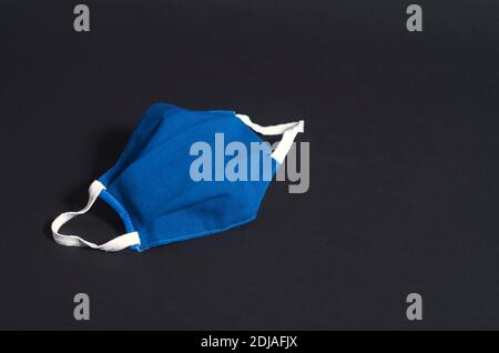 fabric mask with elastics for protection against COVID. Quarantine health measures and social awareness.Isolated object on black background. Stock Photo