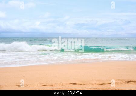 Beautiful blue green aqua waves of the Pacific ocean as it breaks onto beach on sunny but overcast day Stock Photo