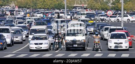 Dubai close up busy wide road junction cars & motorcycles waiting at traffic lights surface car park beyond United Arab Emirates UAE Middle East Stock Photo