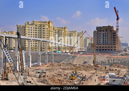 Palm Island cranes & workers on construction building site development below & around overhead monorail railway viaduct Dubai United Arab Emirates UAE Stock Photo