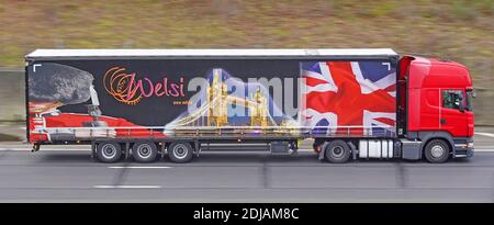 A Red lorry truck & colourful graphics on side curtain of Dutch Welsi international transport business trailer showing London scenes on UK motorway Stock Photo