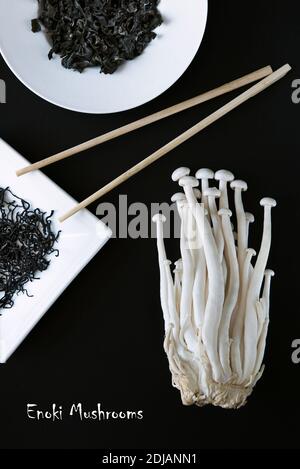 Artistic composition of Asian Food Products - Enoki mushrooms and dry seaweed on a black background. Vegetarian lunch. Healthy food. Concept promotion Stock Photo