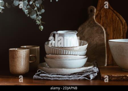Set of kitchen ceramic tableware and wooden cutting boards on a table. Eco style home still life. Stock Photo