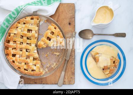 Homemade apple pie with a lattice pastry top and custard Stock Photo