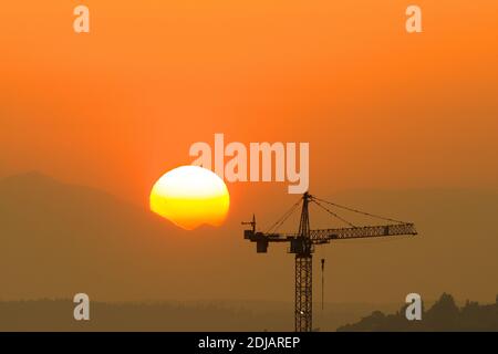 Silhouette of a construction tower against a setting sun. Stock Photo