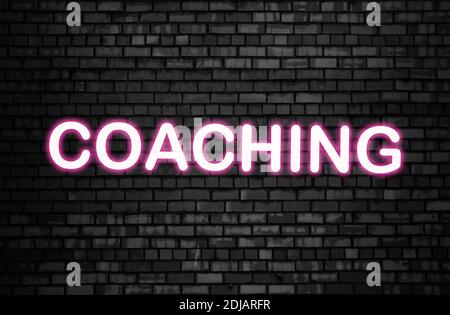 Glowing text "Coaching" on dark brick wall background. Business concept. Internet concept. Education concept. Stock Photo