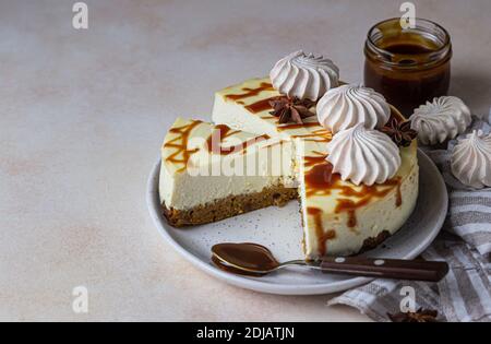 Vanilla cheesecake with carrot cake crust served with salty caramel topping and meringue, light concrete background. Selective focus. Stock Photo