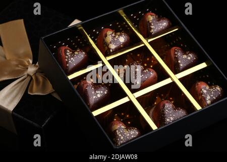 Painted luxury handmade bonbons in a gift box on a black background. Chocolates for Valentine's Day. Stock Photo
