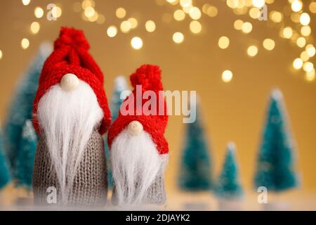 Two Christmas gnomes in red hats on the background of trees and golden lights Stock Photo