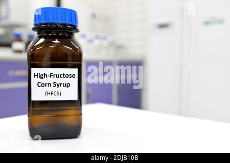 Selective focus of high-fructose corn syrup or hfcs food and beverage sweetener in dark brown glass bottle inside a laboratory. Stock Photo