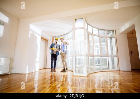 Two young focused engineers looking at and analyzing their plans brainstorming their next step. Architecture and building concept. Stock Photo