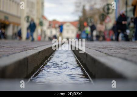 The Freiburg Bächle water runnel viewed in close-up and selective focus with pedestrians blurred in background. Famous historic formalised rills of th Stock Photo