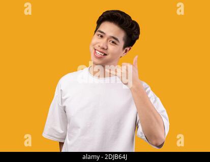 Smiling asian man doing call me phone gesture Stock Photo
