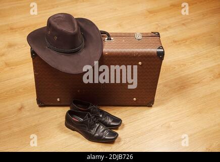 set of men's felt hat, black shoes and a suitcase on a wooden floor Stock Photo