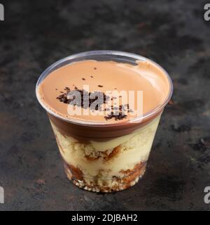 Fast food delivery. Banoffee pie dessert in cup with fresh banana on wooden background, selective focus, copy space, Takeaway box Stock Photo