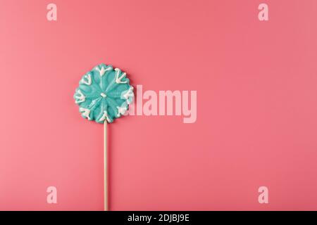 Blue Lollipop in the shape of a snowflake on a pink background. Sweet sugar Lollipop. Minimal flat flat composition, free space Stock Photo
