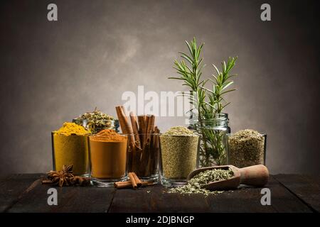 glass jars with various spices on wooden table Stock Photo