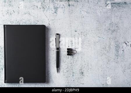 Black Notepad with a black pen on a gray background. Top view, minimalistic concept. Free space. Stock Photo
