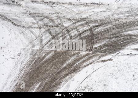 Tracks of car tires in thin layer of first snow in winter. Aerial view Stock Photo