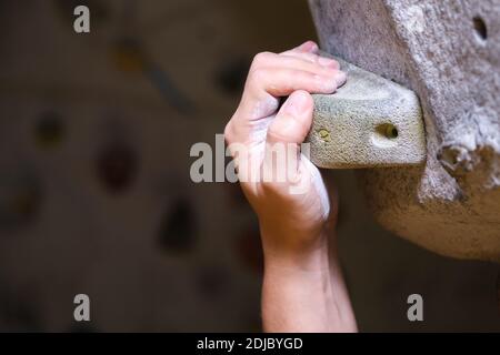 Male hand smeared with magnesium powder grabbing a hold of a climbing wall. Close up detail. Stock Photo