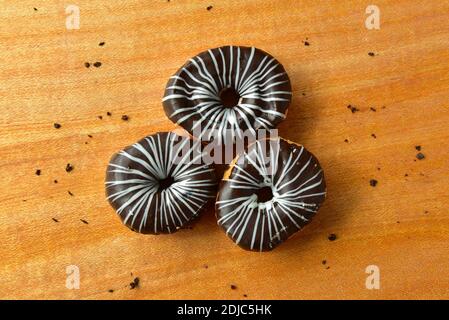 donuts on a wooden background. top view of chocolate donuts with crumbs spread in a wooden background. American desserts, chocolate desserts. Stock Photo