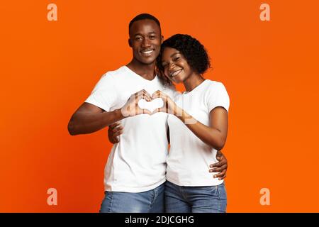 Smiling african lovers making heart shape gesture with hands Stock Photo