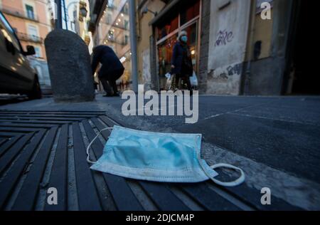 An obviously worn-out mouth and nose protection mask lies thrown away on the street, in Naples city. Stock Photo