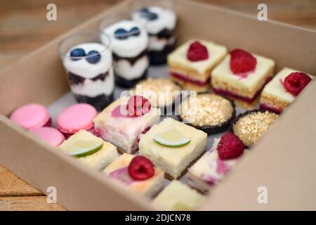 Selection of colorful and delicious cake desserts in box on table. Stock Photo