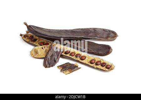 Isolated carob pods. Dried carob pods heap with seeds isolated on white background. Stock Photo