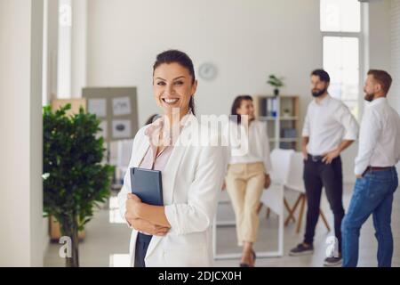 Cheerful female executive manager standing in office after meeting looking at camera and smiling Stock Photo