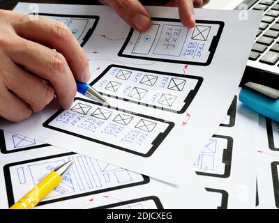 UX designer works with sketches of mobile app and website. Stock Photo