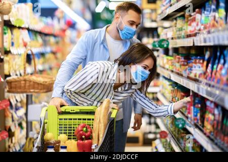 Young couple in protective masks shopping in supermarket Stock Photo