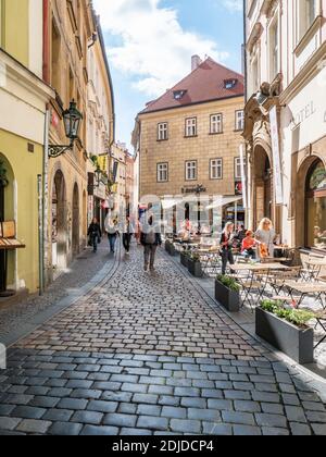 Prague Old Town. A busy urban scene in the narrow cobbled streets of the Czech Republic capital city with shoppers and tourists at a street cafe. Stock Photo