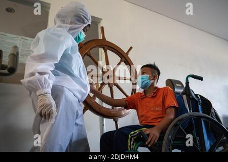 BALI/INDONESIA-OCT 23 2020: a child with a physical disability is doing physical therapy. They wear masks and hamzat suit to avoid the spread of the C Stock Photo