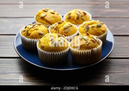 Muffins with pumpkin seeds in blue plate on wooden table. Vegetable cupcakes, healthy food, homemade bake Stock Photo